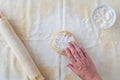 WomanÃ¢â¬â¢s hand dropping flour on ball of cookie dough, pastry cloth, wood rolling pin with cloth cover, small bowl of flour